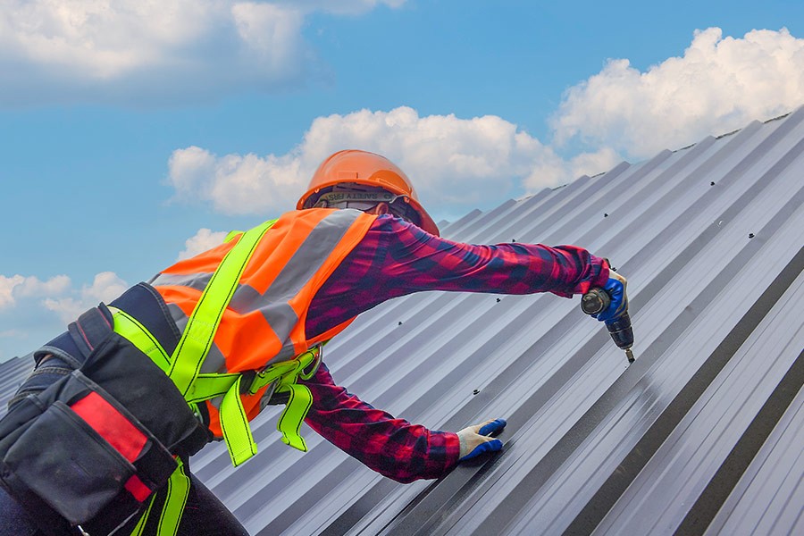 Roofer installing commercial metal roofing on commercial building