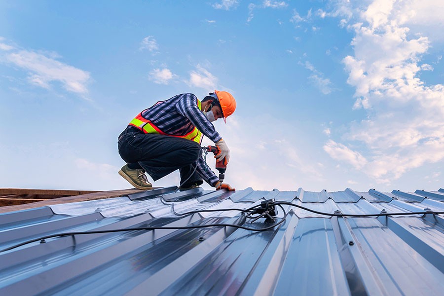 Man replacing roof with metal panels in the summer or spring